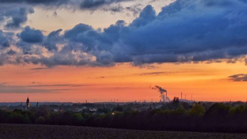 Silhouette of field against cloudy sky at sunset