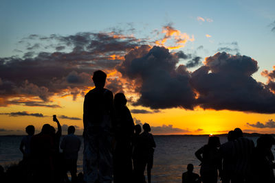 Silhouette people on mountain against sky during sunset