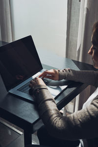 Cropped image of woman using laptop at home