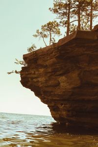 Rock formation by sea against clear sky