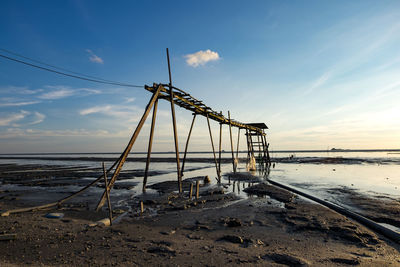 Wooden built structure at sandy beach against sky