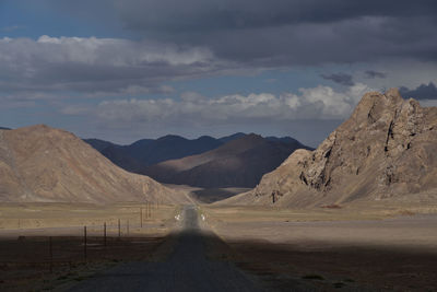 Road leading towards mountains against sky