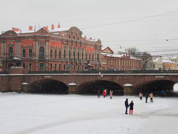 People on snow covered buildings in city