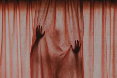 Person hiding behind brown curtain