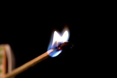Close-up of lit matchstick against black background