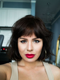 Portrait of beautiful woman wearing lipstick at home