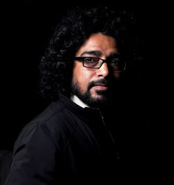 Portrait of young man against black background