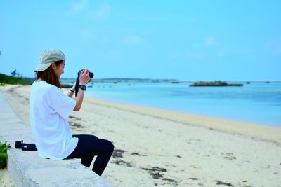 Full length of woman photographing on beach