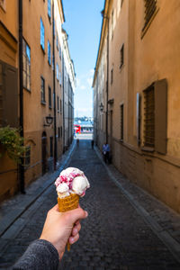 Woman holding ice cream cone on sidewalk