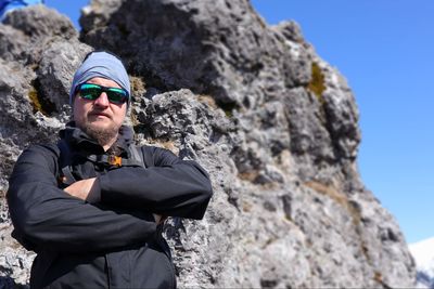 Portrait of young man wearing sunglasses against rock