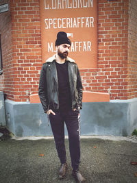 Full length of young man standing against brick wall