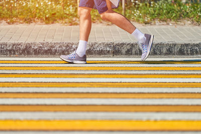 Man running crosswalk, copy space. athletic man jogging in sportswear on city road