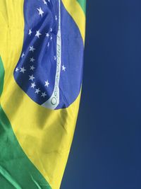 Close-up of yellow flag against blue sky