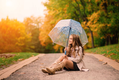 Woman with umbrella standing on road