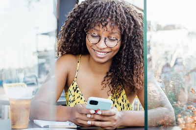 African american female sitting at table in cafe and chatting on social media while relaxing during weekend in city