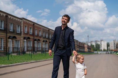 Full length of smiling young man standing against sky