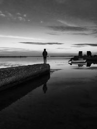 Rear view of silhouette man standing on beach against sky