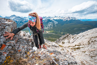 Female scrambling mountain ridge above kananskis country in rockies