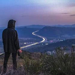 Rear view of man looking at cityscape against sky