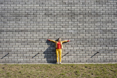 Woman standing at a brick wall listening to music with headphones