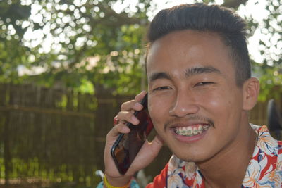 Close-up portrait of smiling young man talking on phone