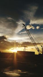 Cranes against dramatic sky during sunset