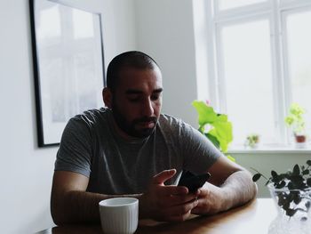 Young man using mobile phone at home