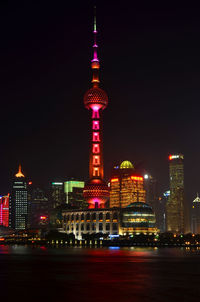 Illuminated tower in city against sky at night