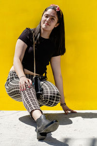 Portrait of smiling young woman against yellow wall