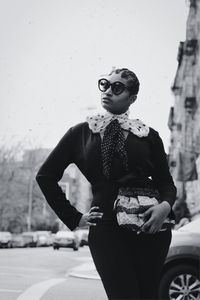 Young woman wearing sunglasses standing against built structure