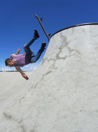 Low angle view of man jumping against clear sky