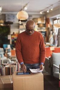 Senior man using digital tablet on box at store