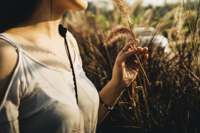 Midsection of woman holding plant on field