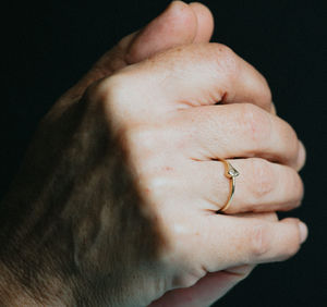 Cropped hand of woman holding wedding ring against colored background