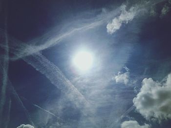 Low angle view of sun shining through clouds