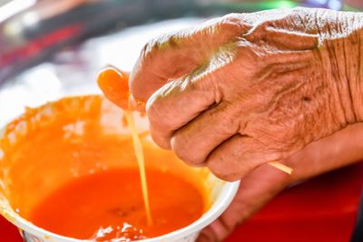 Close-up of hand holding orange bowl