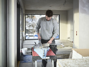 Tiler cutting tiles with equipment at construction site