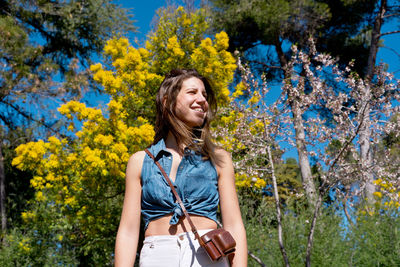 Portrait of young woman standing by plants