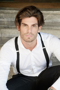 Portrait of man wearing suspenders while sitting on steps