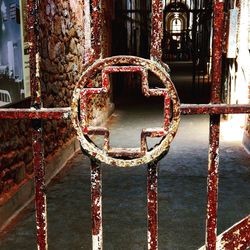 Rusty chain hanging on metal gate against building