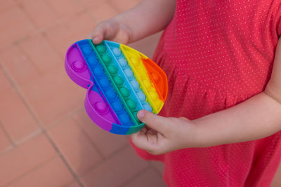 Midsection of woman holding multi colored umbrella