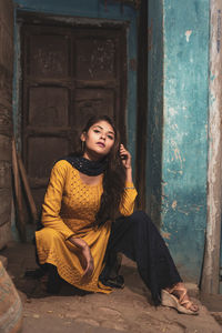 Portrait of a young woman sitting on door