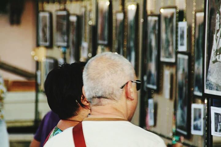 lifestyles, focus on foreground, leisure activity, headshot, rear view, casual clothing, head and shoulders, person, men, waist up, incidental people, standing, indoors, architecture, built structure, young adult, front view, building exterior