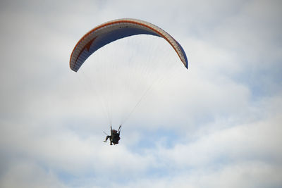 Low angle view of person paragliding against sky