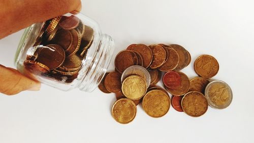 Close-up of hand holding coins over white background