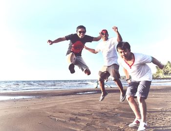 Full length of man jumping on beach against sky