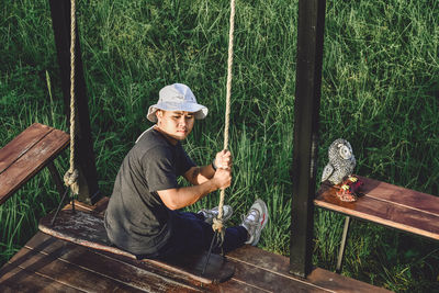 Young man sitting on chair against plants