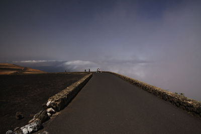 Road amidst land against sky