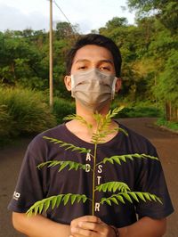 Portrait of young man standing against plants