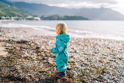 Rear view of boy standing at beach